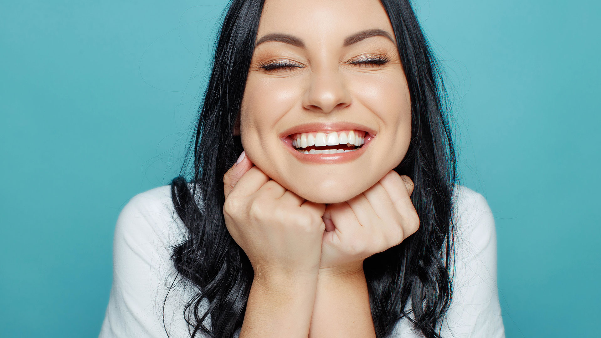 The image is a split-screen photograph of a woman with a radiant smile, one half showing her face and the other half showing her hands clasped together in front of her.