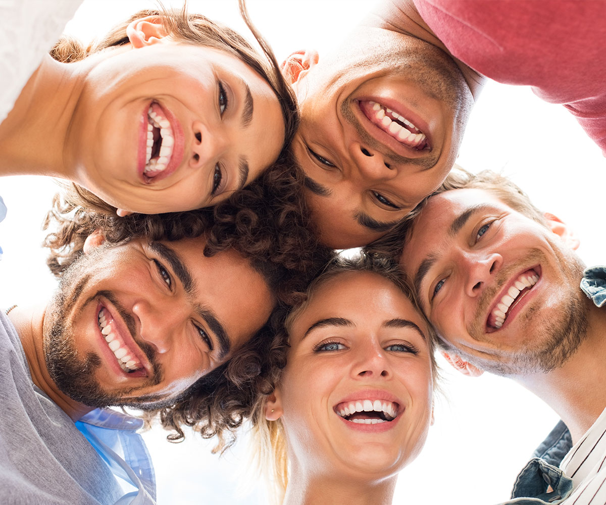 A group of six young adults, likely friends or a family, smiling and posing together for a photo.