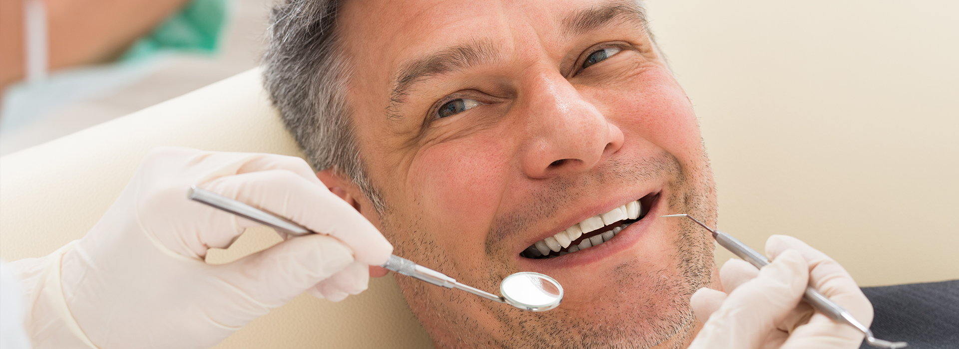 Man in a dental chair receiving a dental procedure, with dental tools visible.