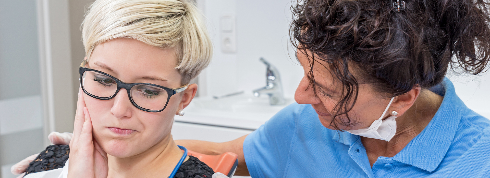 The image shows a woman receiving dental care from a professional in a clinical setting.