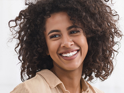 The image features a woman with curly hair, smiling and looking directly at the camera.